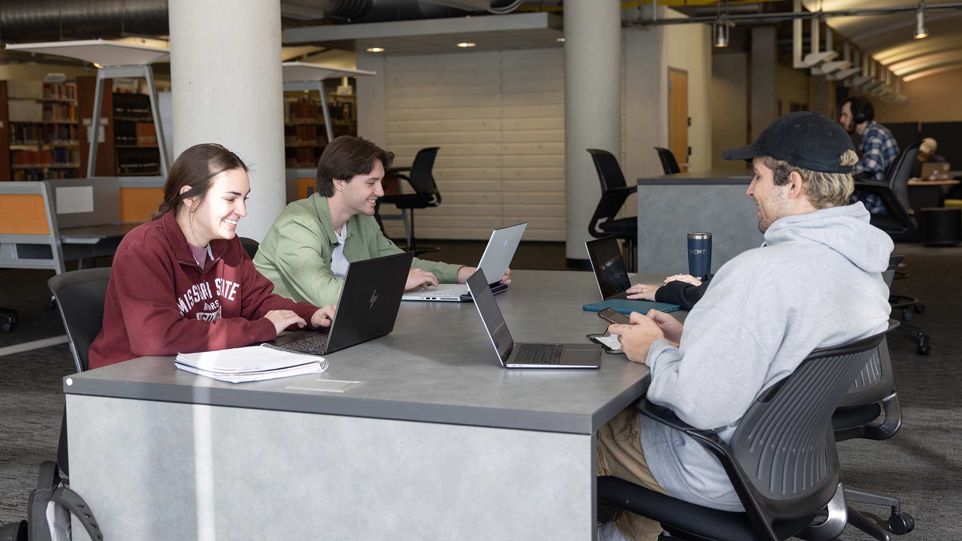 Three students studying on their laptops at a table in Meyer Library.