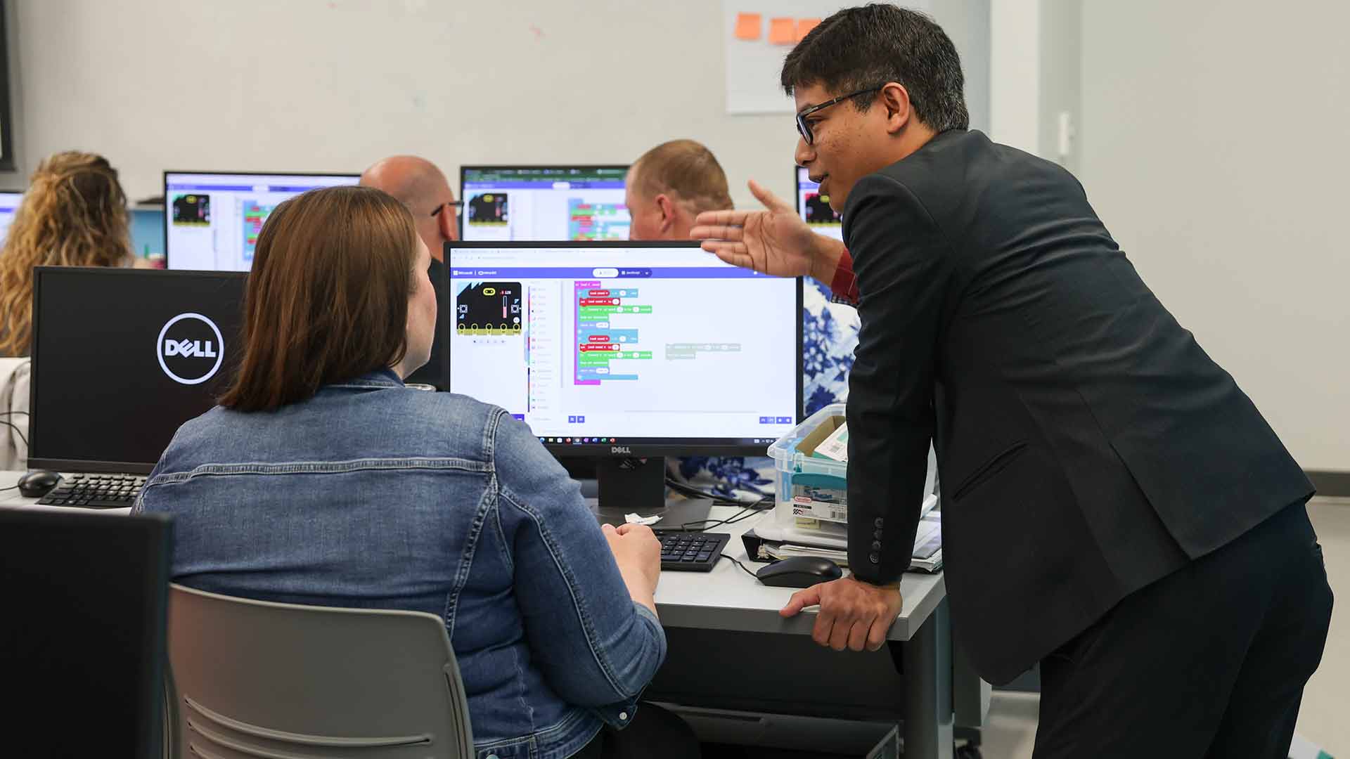 A professor instructs a student during a computer science workshop.