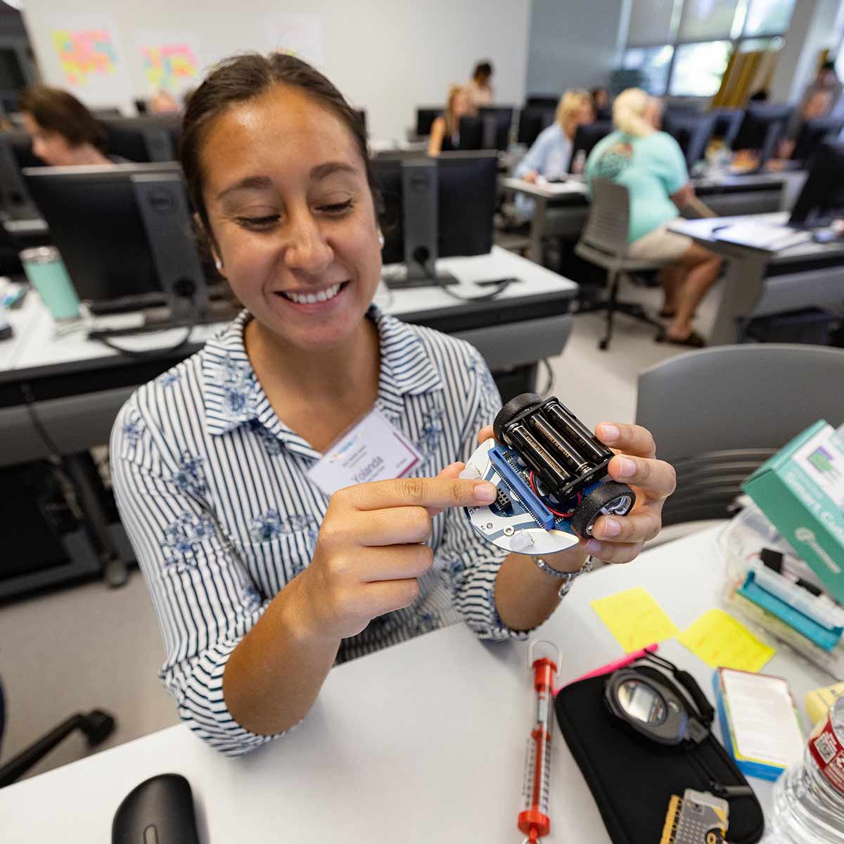 A smiling student holds a device during a computer science training workshop.