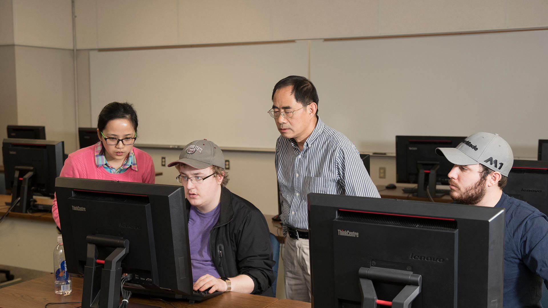 Mathematics professor Dr. Xingping Sun and three students look at math problems on a computer during class.