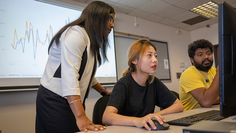 A professor helping two students in a data visualization class.